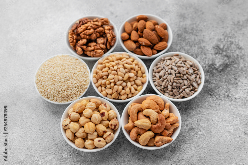 Assortment of nuts in white saucers on a concrete background. Food mix background, top view, copy space, banner Assortment of nuts in white saucers on a concrete background. Food mix background, top view, copy space, banner