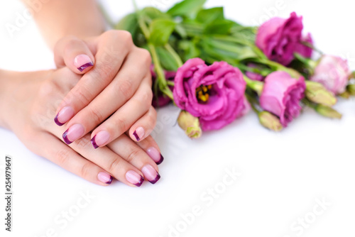 Hands of a woman with pink french manicure and flowers eustoma on a white background