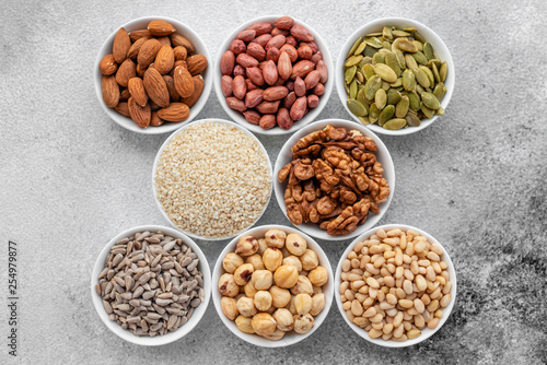Assortment of nuts in white saucers on a concrete background. Food mix background, top view, copy space, banner