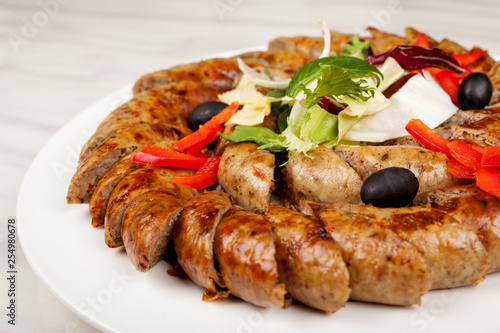 Baked sausage sliced with vegetables on a large platter.