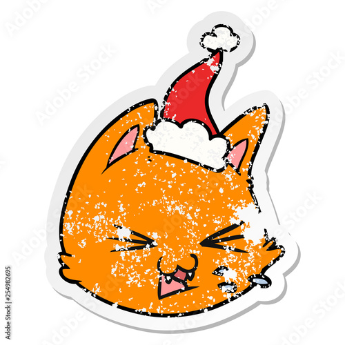 spitting distressed sticker cartoon of a cat face wearing santa hat
