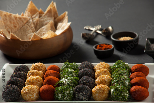 Cheese platter, appetizer. Spicy, sesame, blue poppy, red pepper, parsley cheese balls. With whole wheat chips