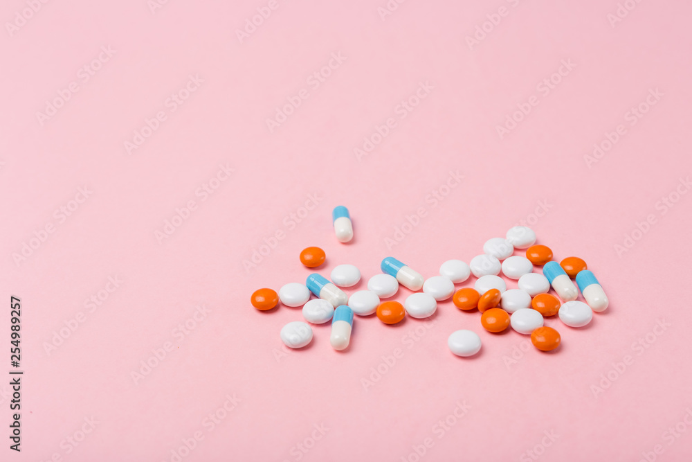 Obraz premium Different pharmaceutical medicine pills, tablets and capsules on light pink background. Copy space. Medicine medical concept. Be healthy. Selective focus.