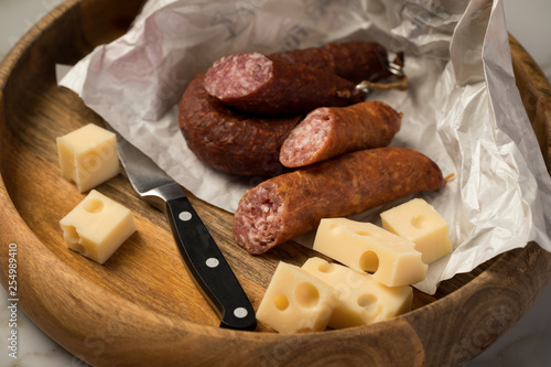 Ringwurst Salami, Bierbeißer Wurst und Edamer Käse in Wachspapier mit Messer auf Vesper Holzbrett photo