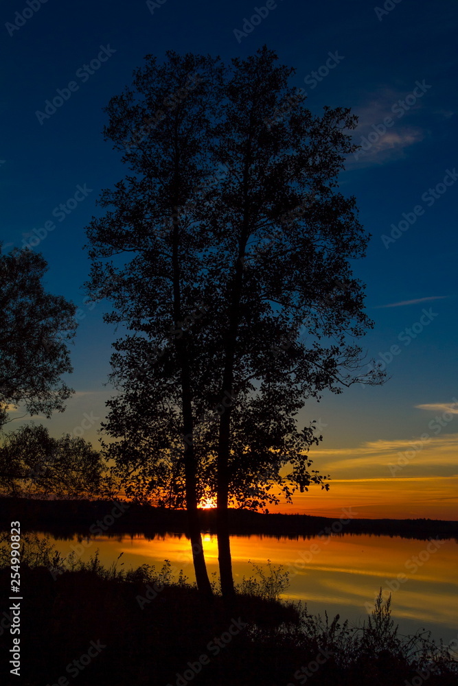 Late autumn sunset on the lake against the silhouette of two trees. Late autumn sunset on the lake against the silhouette of two trees.