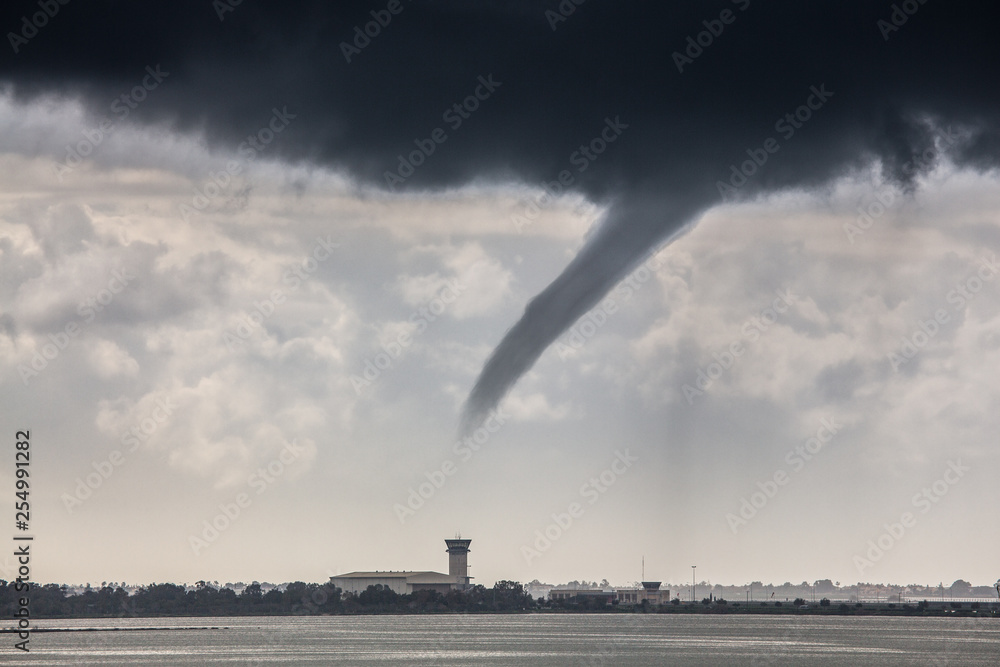 A rope tornado above the runway and airport traffic control tower. Danger for traffic air transport. Bad weather report. Traffic delays. A rope tornado above the runway and airport traffic control tower. Danger for traffic air transport. Bad weather report. Traffic delays.