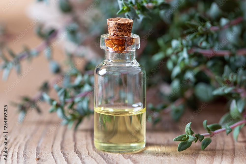 A bottle of thyme essential oil with fresh thyme twigs A bottle of thyme essential oil with fresh thyme twigs