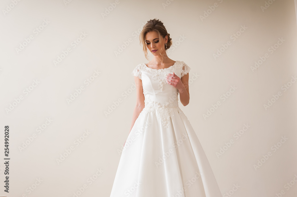 Fashion bride in gorgeous wedding dress studio portrait. Beautiful model with bridal makeup and hairstyle in marriage lace dress.