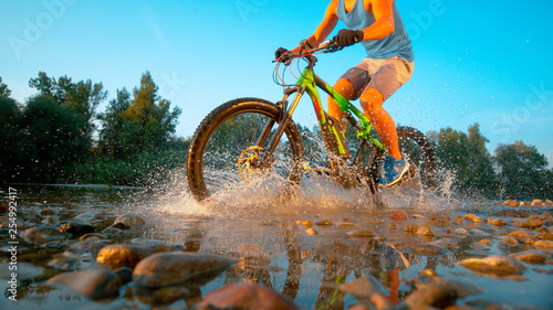 LOW ANGLE: Unrecognizable male mountain biker splashes the pure river water.