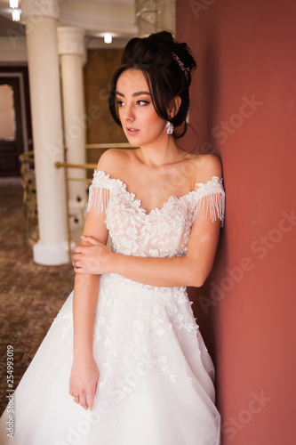 Beauty portrait of bride wearing fashion wedding dress with feathers with luxury delight make-up and hairstyle, studio indoor photo