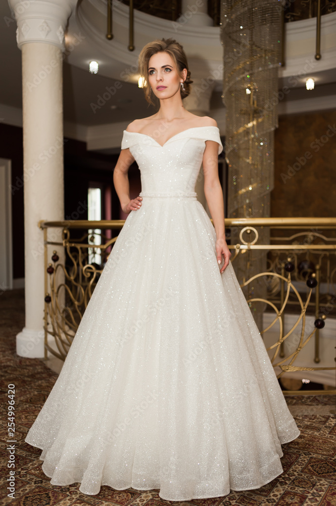 Naklejka premium Portrait of a beautiful bride woman in elegant white wedding dress. Luxurious apartments. 