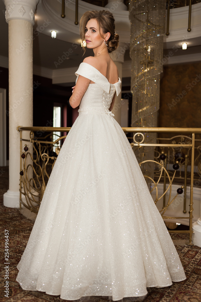 Fototapeta premium Portrait of a beautiful bride woman in elegant white wedding dress. Luxurious apartments. 