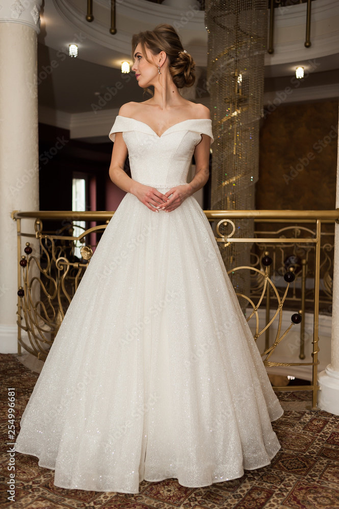 Fototapeta premium Portrait of a beautiful bride woman in elegant white wedding dress. Luxurious apartments. 