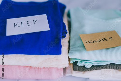 Fotografie piles of tshirts and clothes being sorted into Keep Discard and Donate categorie