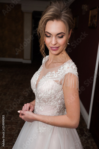 Beauty portrait of bride wearing fashion wedding dress with feathers with luxury delight make-up and hairstyle studio indoor photo.