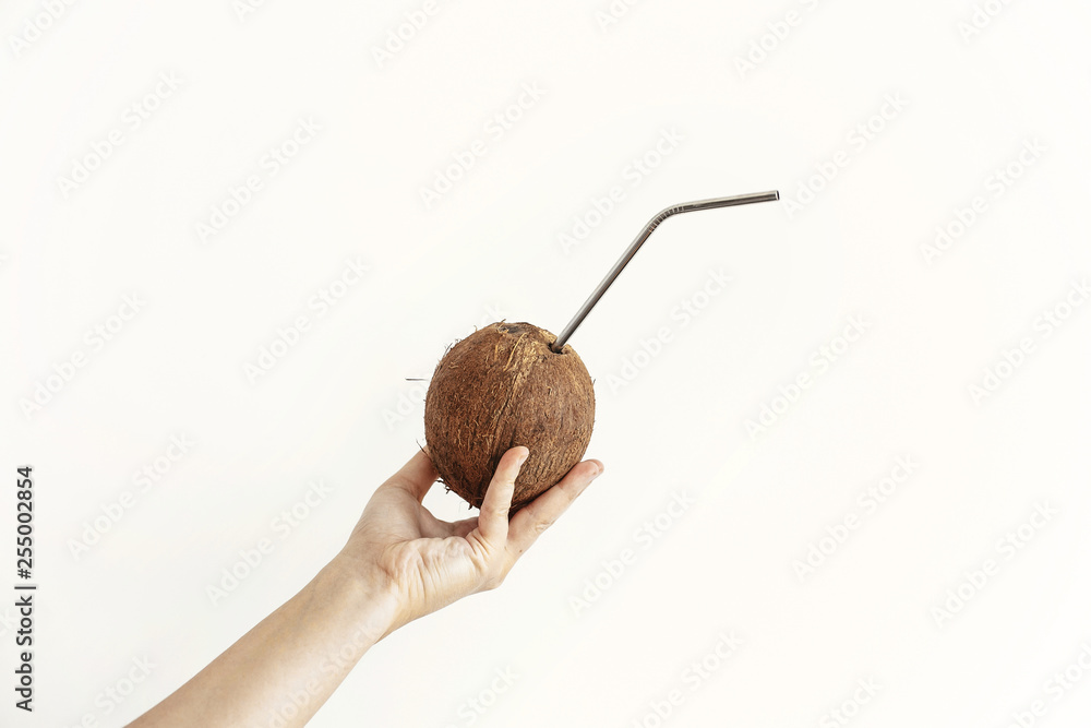 Zero waste. Hand holding coconut with metal straw on white background. Hello summer vacation concept. Ban plastic, ecological problem. Sustainable lifestyle on tropical island. Copy space Zero waste. Hand holding coconut with metal straw on white background. Hello summer vacation concept. Ban plastic, ecological problem. Sustainable lifestyle on tropical island. Copy space