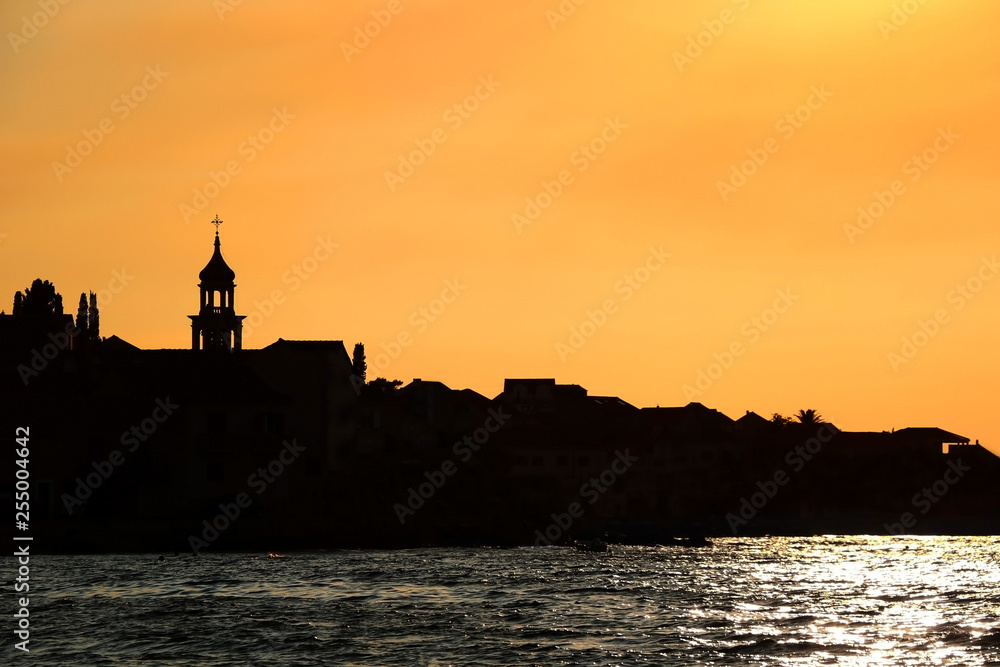 Sunset over Sutivan, small town on island Brac, Croatia. Silhouette view of landmark baroque bell tower.