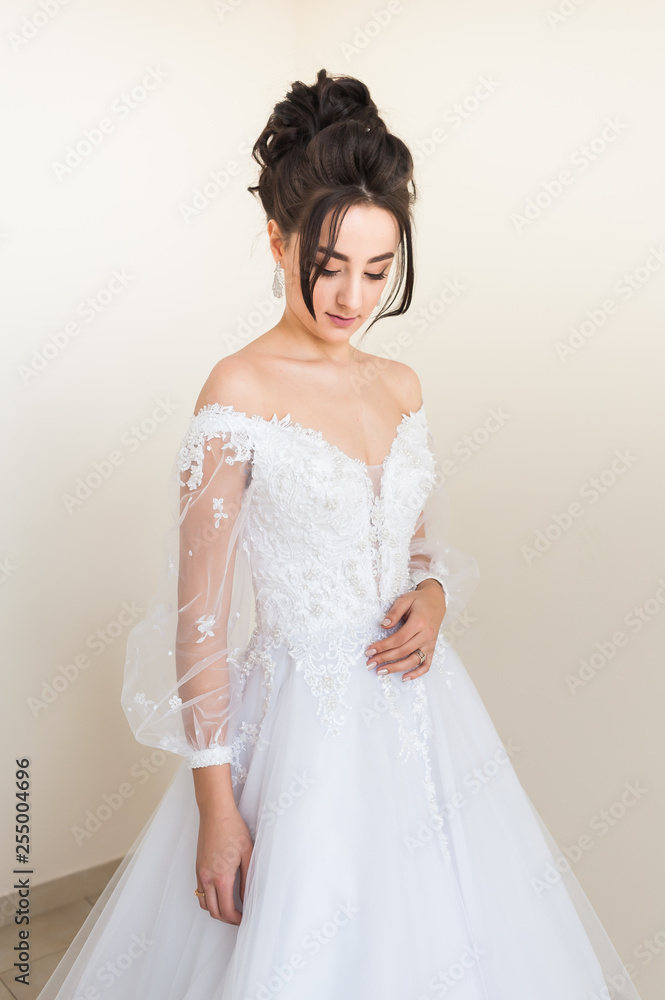 Beautiful bride wearing fashion wedding dress with feathers with luxury delight make-up and hairstyle studio indoor photo shoot Beautiful bride wearing fashion wedding dress with feathers with luxury delight make-up and hairstyle studio indoor photo shoot