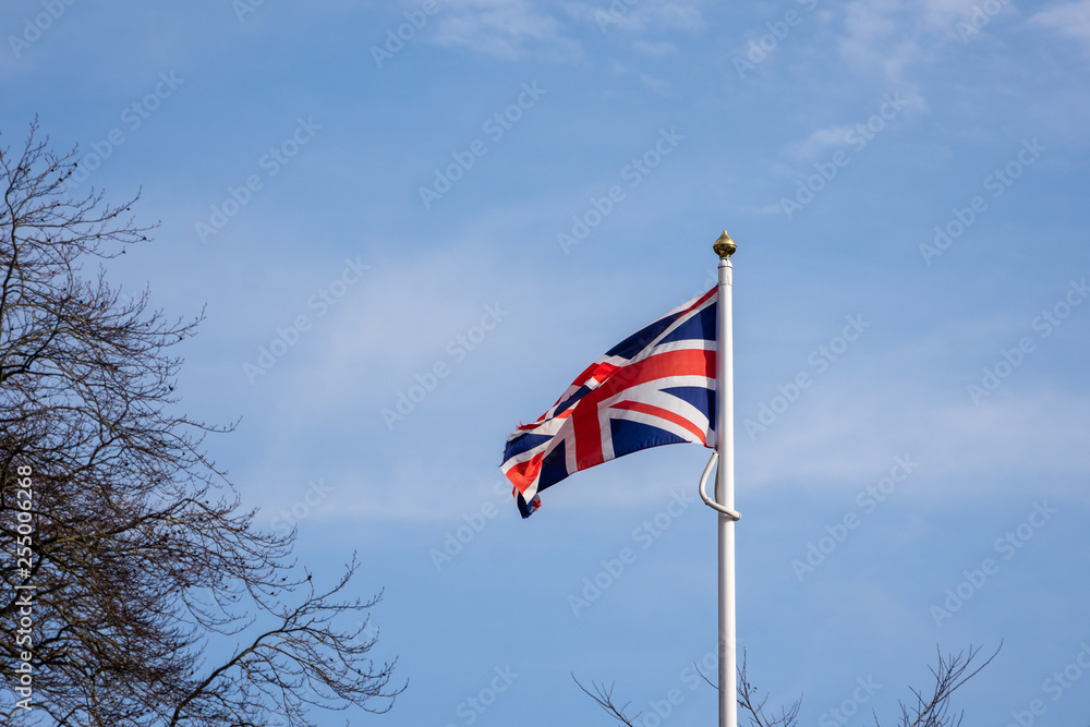Union Jack flag against blue sky with clouds