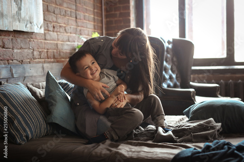 Konstfotografi happy real mom and boy son hug and play on bed