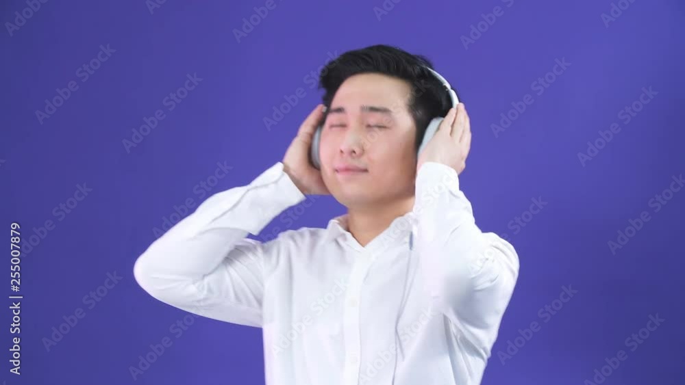 Studio portrait of handsome young man of Japanese ethnicity and headphones, enjoying listening to music Studio portrait of handsome young man of Japanese ethnicity and headphones, enjoying listening to music