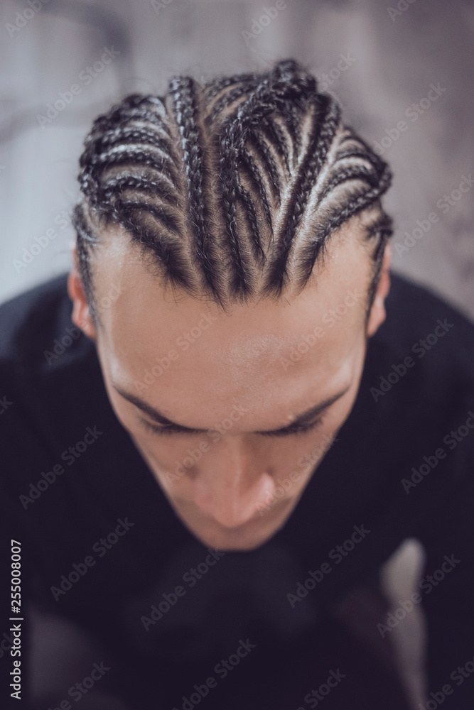 male hairstyle close-up braids, hair braided, pensive look, man portrait  Stock Photo