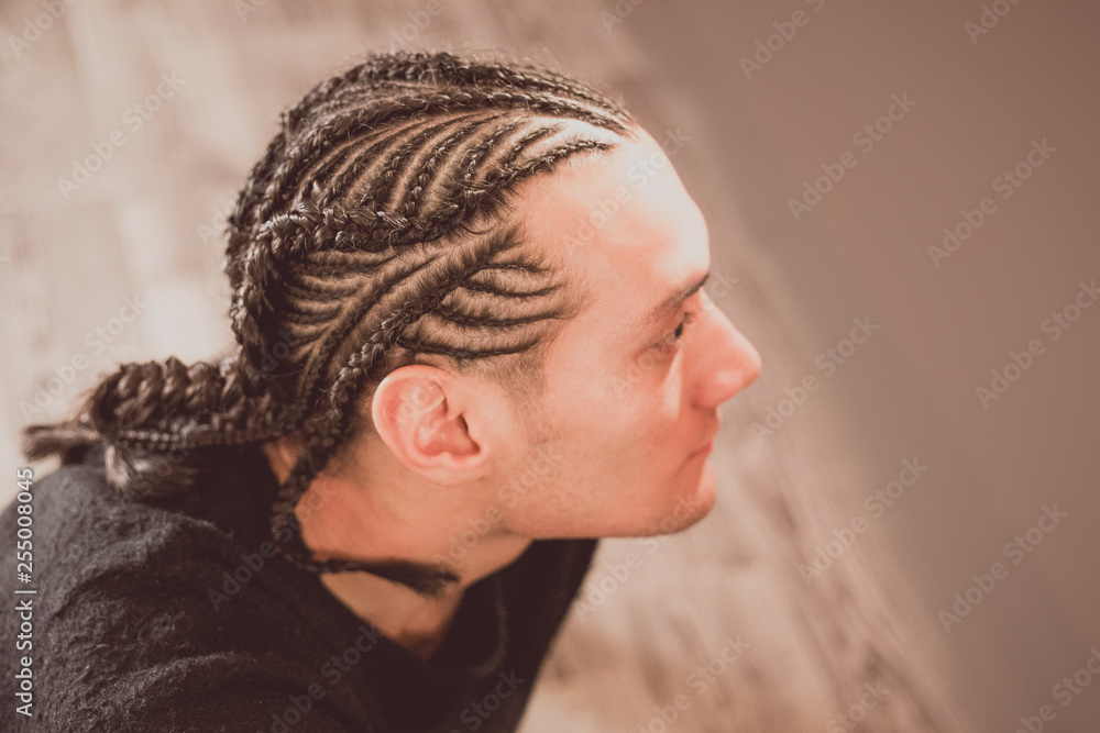 male hairstyle close-up braids, hair braided, pensive look, man portrait  Stock Photo