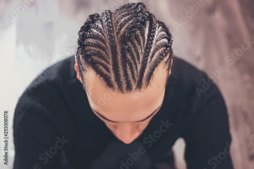 male hairstyle close-up braids, hair braided, pensive look, man portrait