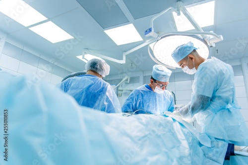 Surgeons in binocular lenses operate the patient lying under anesthesia in the operating room