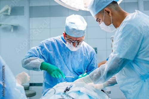 Surgeons in binocular lenses operate on the patient lying under anesthesia