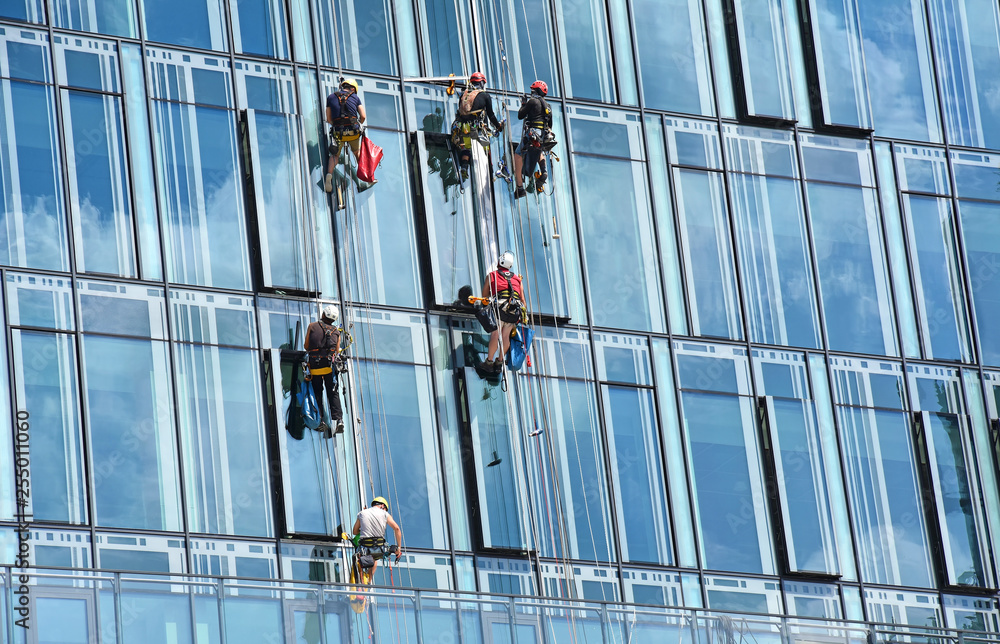 Group of construction workers working at height on modern commercial skyscraper, teamwork