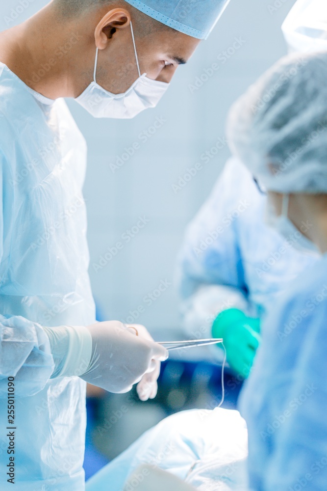 Surgeons perform a complex operation sewing up a wound to a sick patient. Vertical photography Surgeons perform a complex operation sewing up a wound to a sick patient. Vertical photography