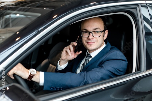 Businessman sitting behind the wheel of a car talking on a mobile phone