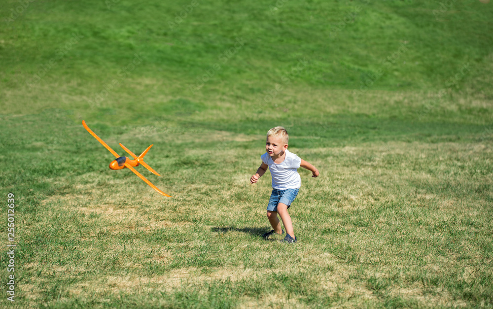 Fototapeta premium Young boy playing airplane on the meadow
