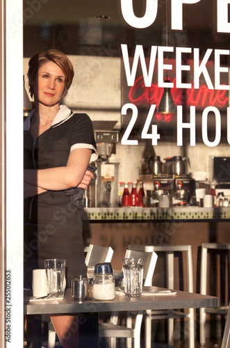 Waitress restaurant server looking out cafe diner window with a hopeful expression. Unskilled service worker.