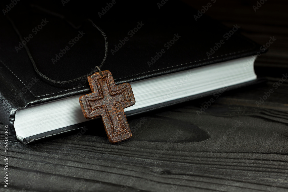 leather cross near the book on the table