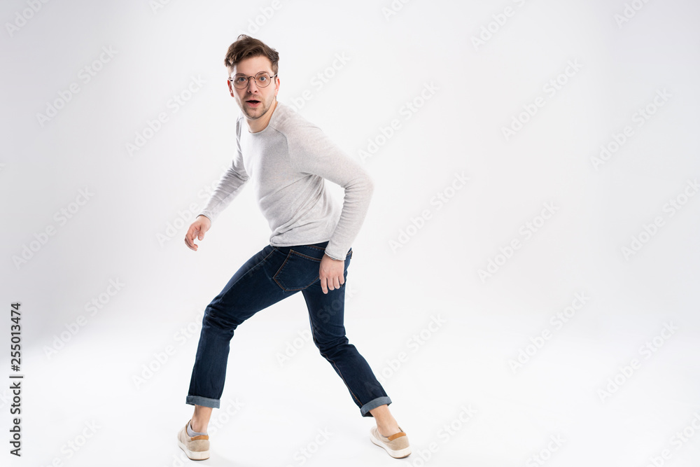 Funny man in casual is having some fun. He is posing and dancing. Isolated on white background.