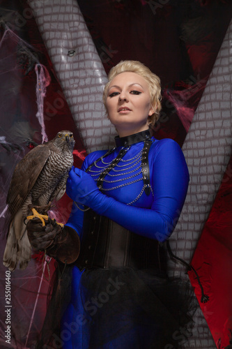 beautiful scary woman with the big hawk best friend on the background of dark room photo