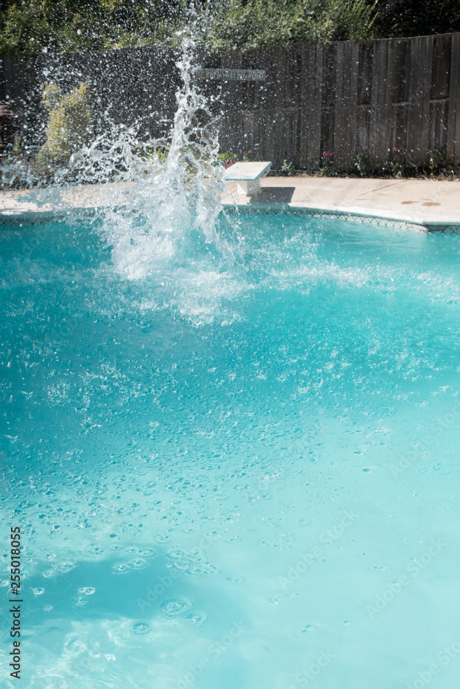 Guy jumps into an outdoor swimming pool in the summer. Man lands in