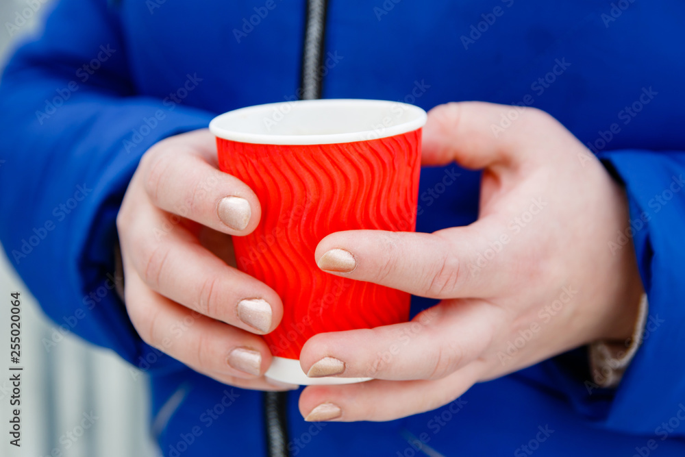 Obraz premium Hot drink coffee in paper cup in women's hands close up