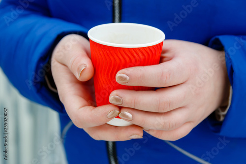 Hot drink coffee in paper cup in women's hands close up