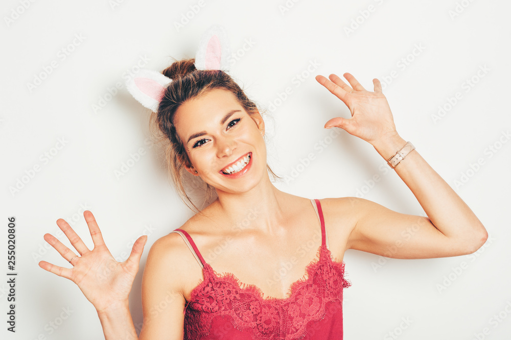 Studio shot of beautiful young woman wearing bunny ears, posing on white background, Easter concept Studio shot of beautiful young woman wearing bunny ears, posing on white background, Easter concept