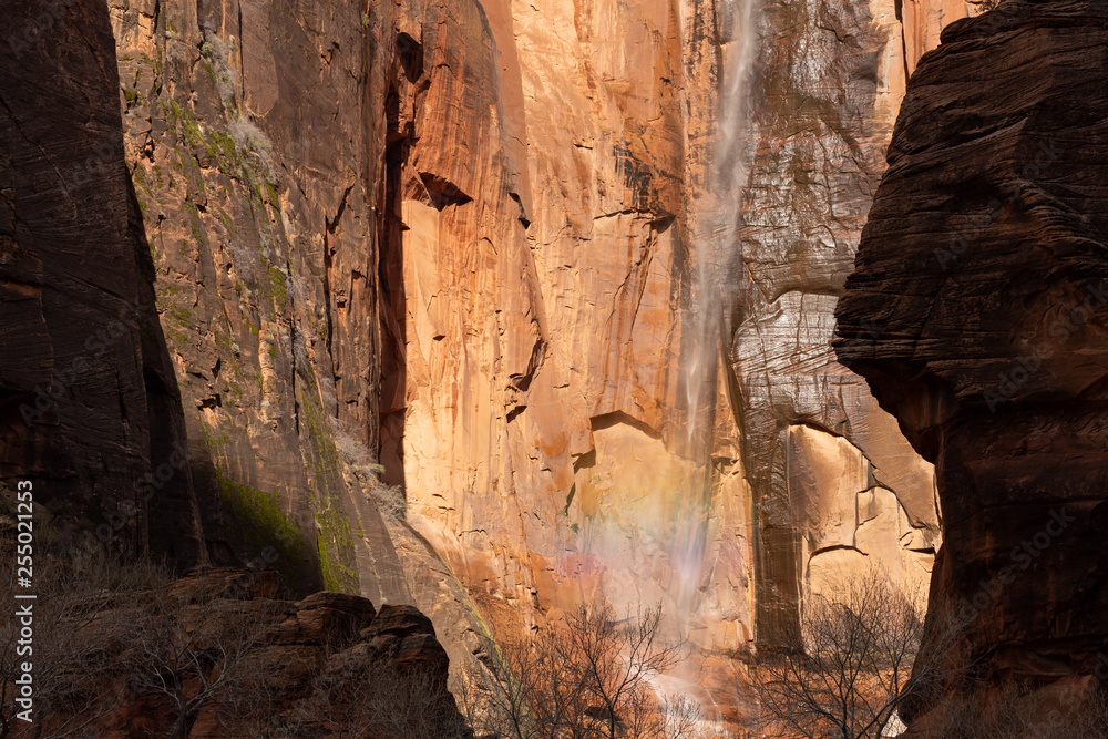 The waterfall at the Temple of Sinewava reflects a bit of rainbow as sunshine lights the cliff face. 