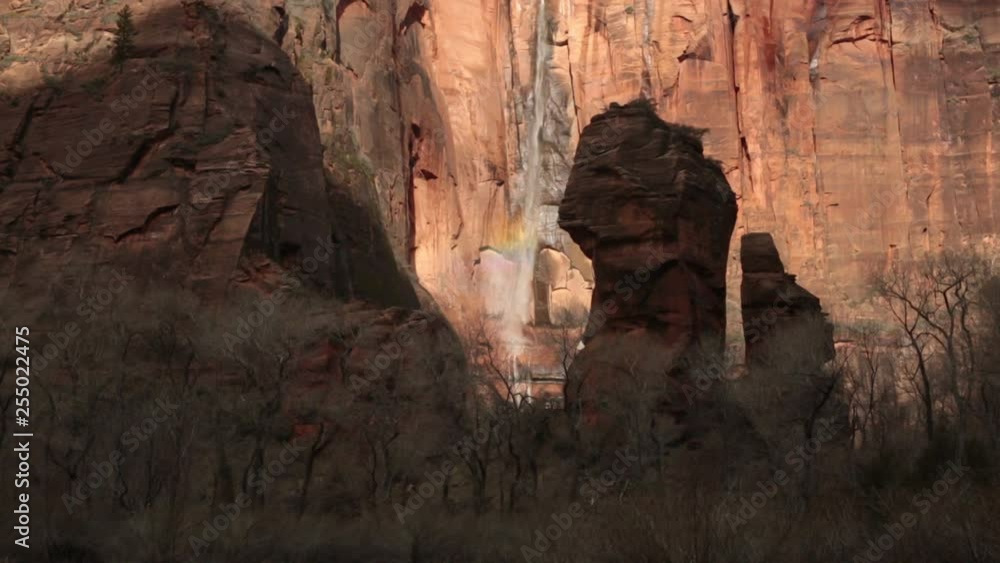 Water cascades down the cliff face at the Temple of Sinewava in Zion national park Utah on a winter morning while the sun makes rainbows in the spray and cloud shadows slide across the mountain. Water cascades down the cliff face at the Temple of Sinewava in Zion national park Utah on a winter morning while the sun makes rainbows in the spray and cloud shadows slide across the mountain.