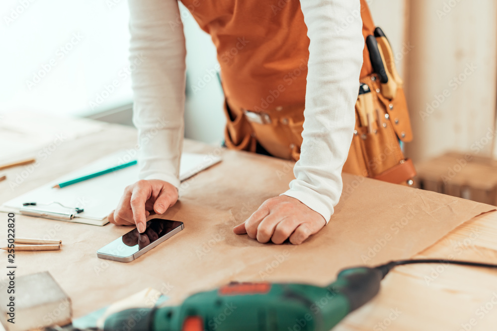 Female carpenter using smartphone Female carpenter using smartphone