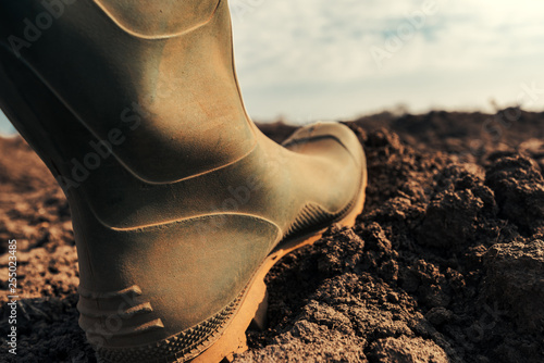 Fotografi Farmer in wellington rubber boots making first step in field