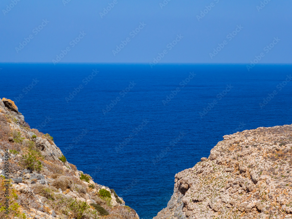 View of endless blue sea, two rocky hills meet in the foregorund