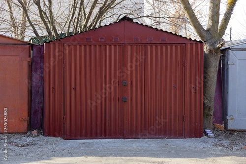 large red metal garage with closed gates standing outside © butus