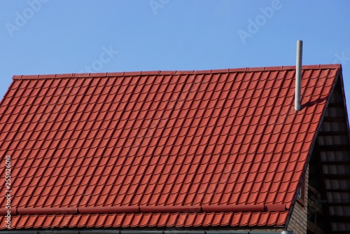 red tile roof with chimney against the blue sky
