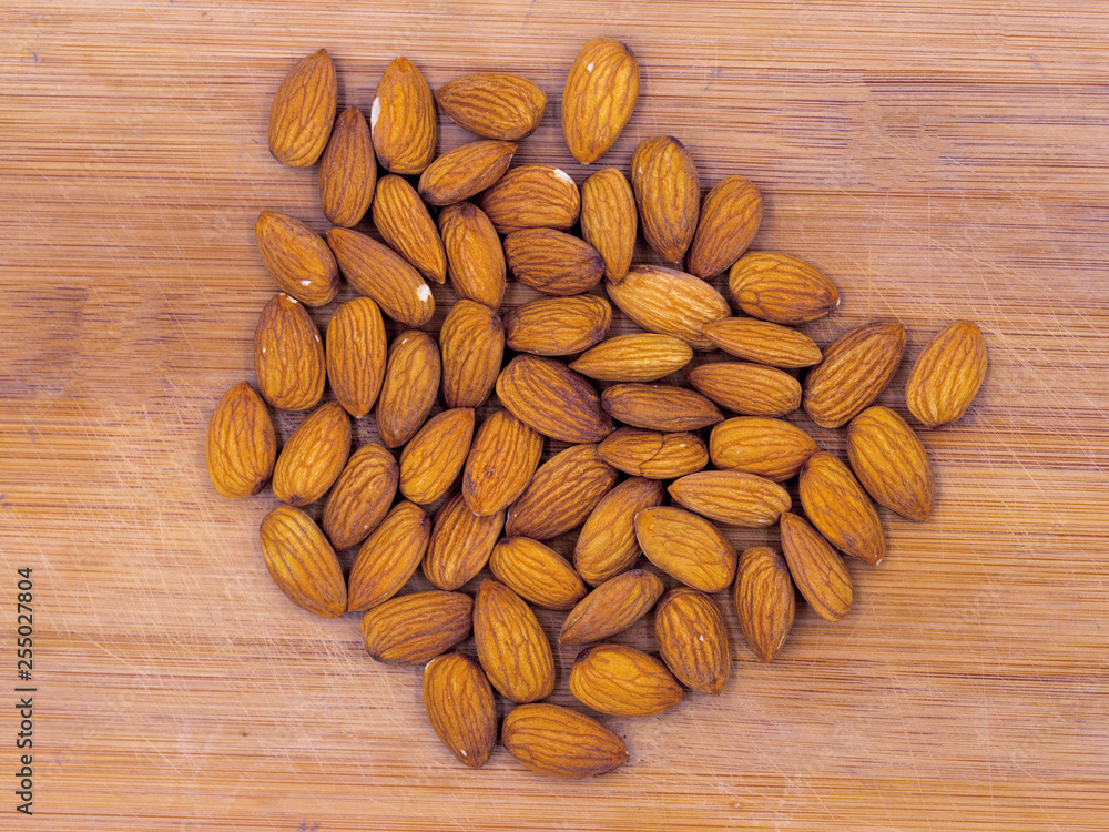 Almond heap on timber background, top view photo. Tasty healthy snack. Scattered nuts on table. Organic food Almond heap on timber background, top view photo. Tasty healthy snack. Scattered nuts on table. Organic food